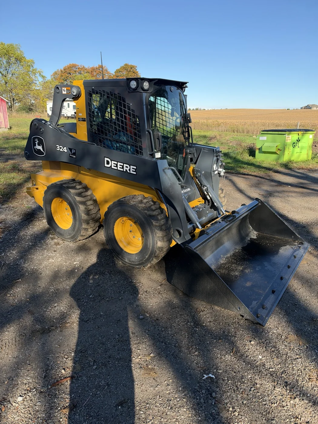John Deere skid steer with a front bucket parked on a paved driveway